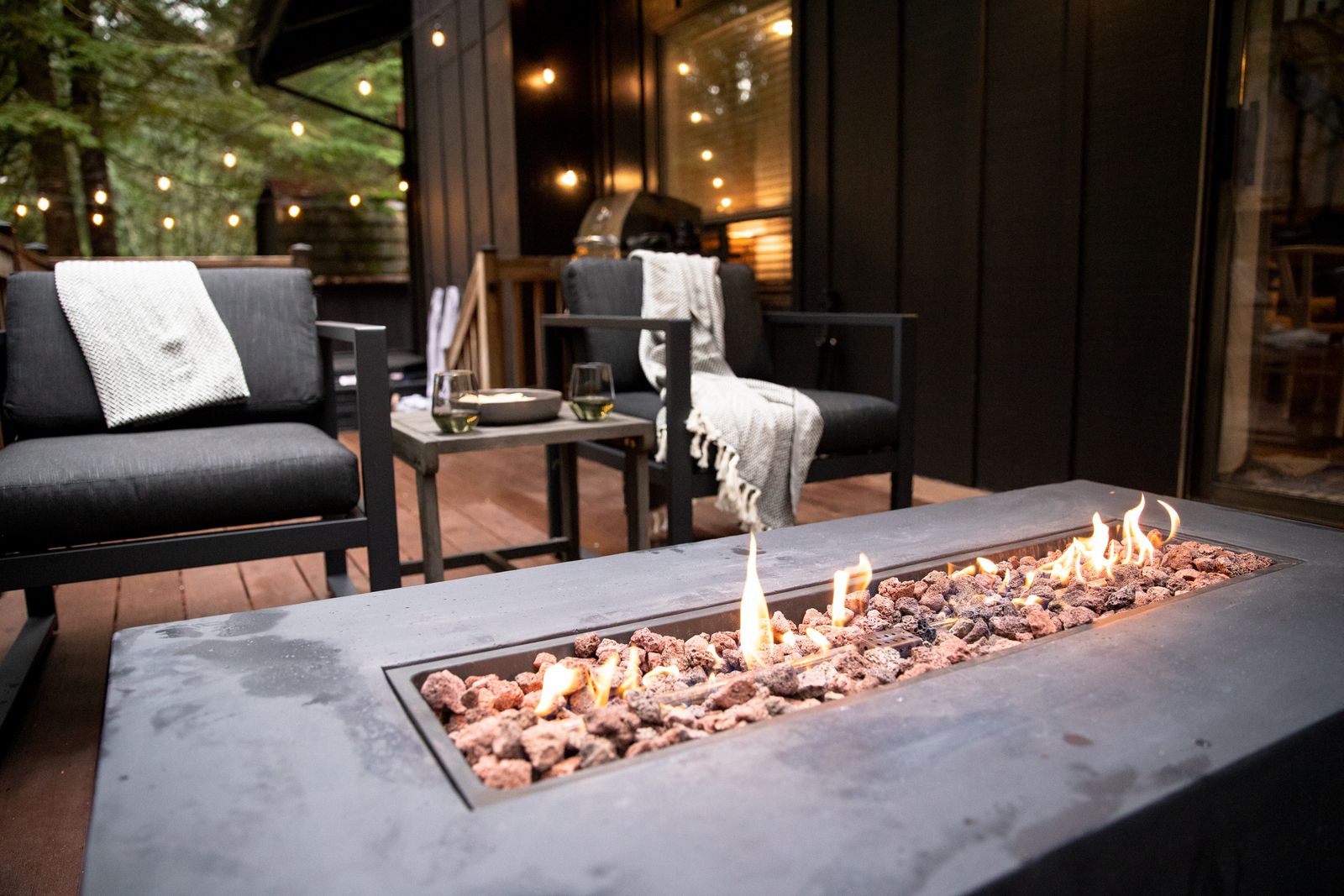 Deck with a gas fire table, lounge chairs and string lights