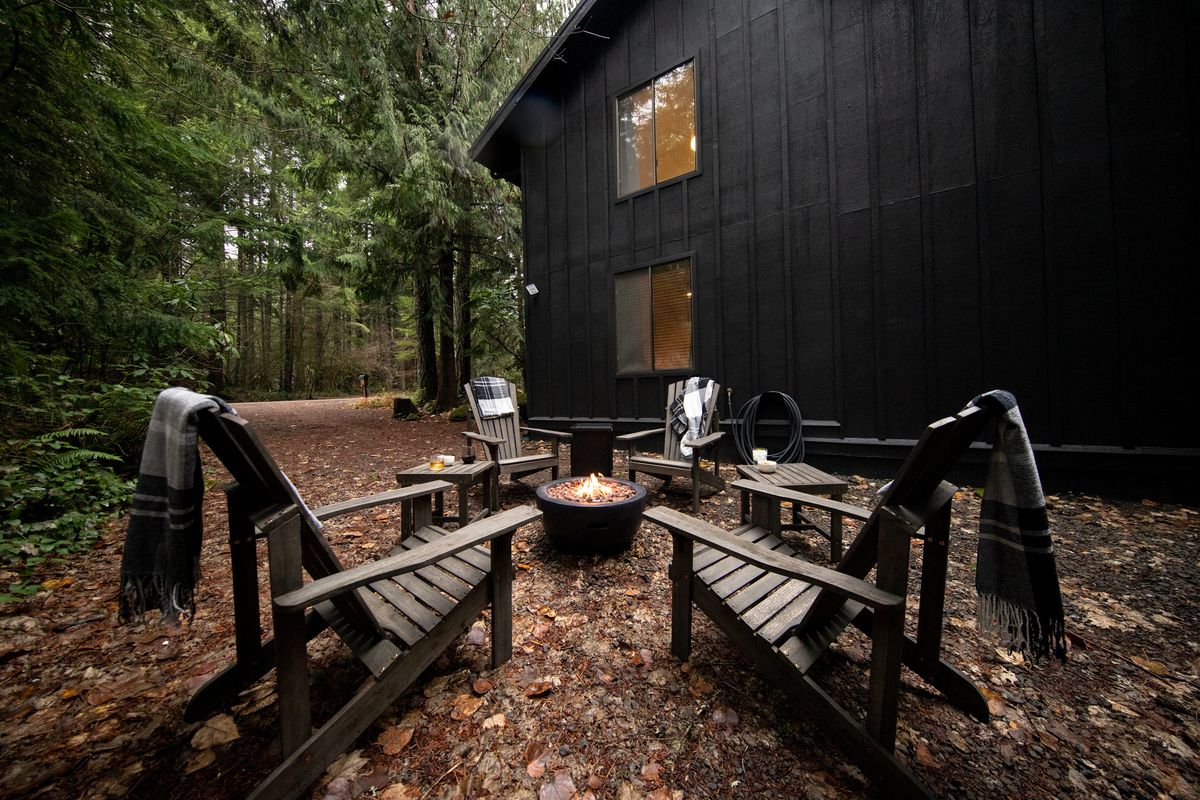 Fire pit ringed by Adirondack chairs in the forest